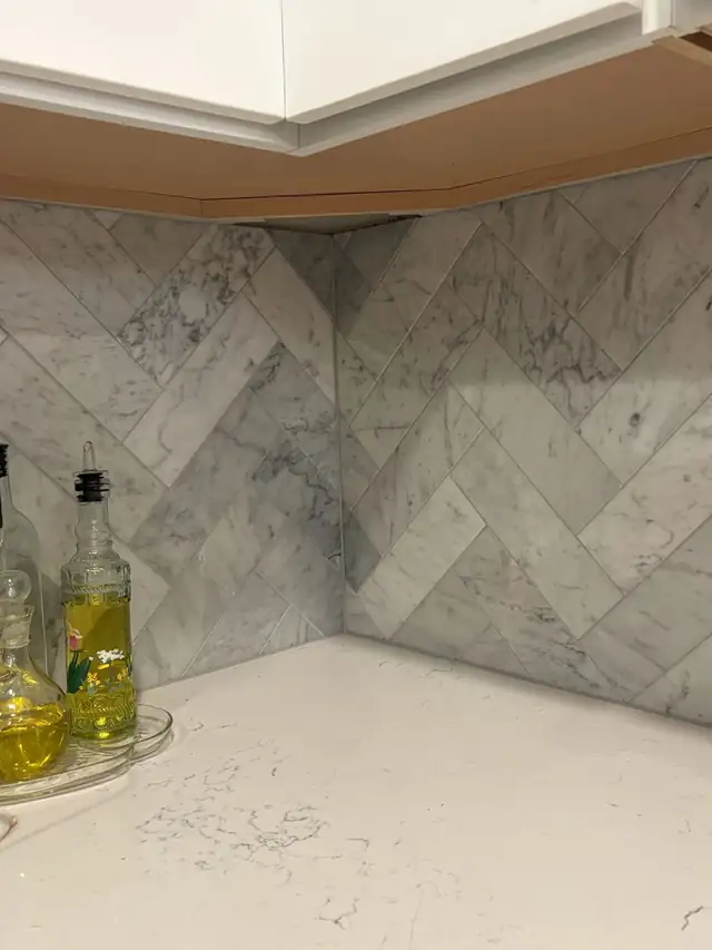 Herringbone marble backsplash meeting at a book-matched inside corner