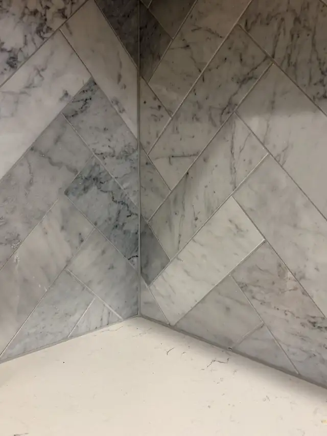 Herringbone marble backsplash laid into a book-matched inside corner